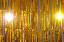 Metallic Tinsel Background. Bright Gold Foil Fringe Curtains Hung As Interior Decor Or Photo Backdrop At A Party. Sparkling Mylar Decoration For Festive Events. Shiny Golden Streamers Hanging Off Door