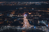 Fototapeta Miasto - Drone view at night, with illuminated streets and dark sky. Beautiful cityscape