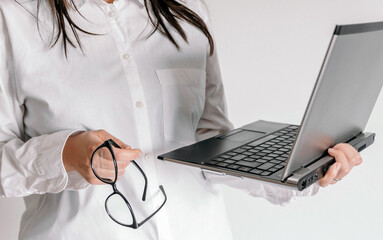 Wall Mural - Closeup of female holding eyeglasses and a laptop