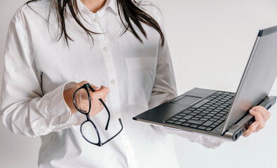 Wall Mural - Closeup of female holding eyeglasses and a laptop