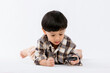 © kanpisut - Child holding magnifying glass on white background. Boy with a magnifying glass in studio. Positive curious boy in casual wear looking at through magnifier