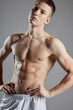 © SHOTPRIME STUDIO - athlete with pumped up abs holding hands by belt on gray background cropped view
