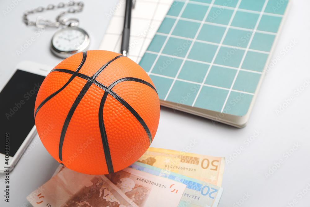 Money, mobile phone and ball for playing basketball on table. Concept of sports bet