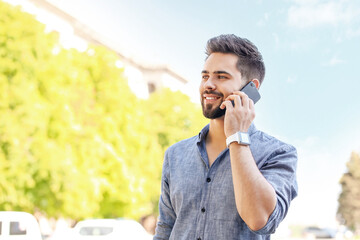 Poster - Handsome man with modern wristwatch talking by mobile phone outdoors