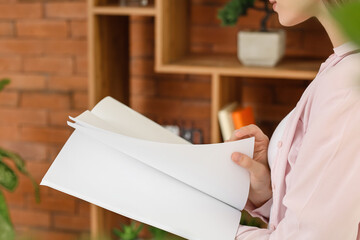 Canvas Print - Young woman reading blank magazine in room