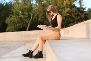 Canvas Print - Beautiful woman reading blank magazine outdoors