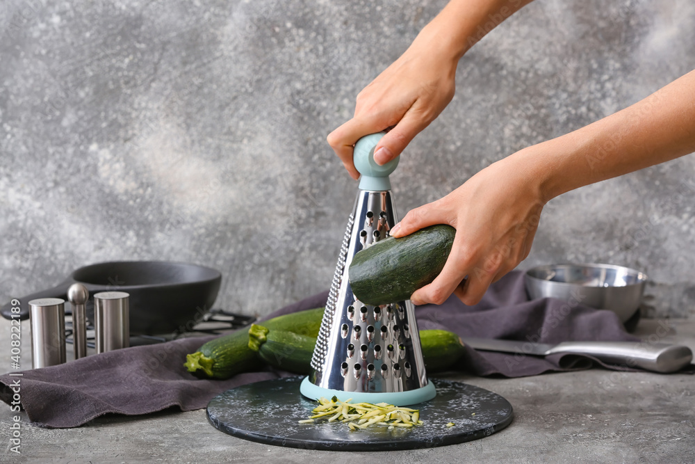 Woman grating zucchini at table