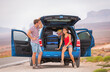 © Maridav - Car travel road trip couple of happy man and Asian woman packing luggages in the trunk of SUV driving on adventure road in the USA. Summer vacation destination friends traveling. Outdoor lifestyle.
