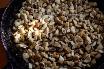 Raw mushrooms are fried in a pan.