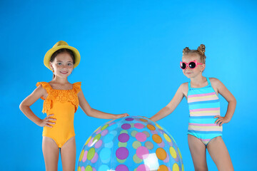 Canvas Print - Cute little children in beachwear with inflatable ball on light blue background