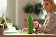 © New Africa - Woman taking green thermos bottle at workplace, closeup