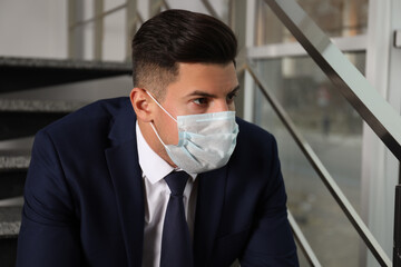 Canvas Print - Sad man in protective mask on stairs indoors. Self-isolation during coronavirus pandemic