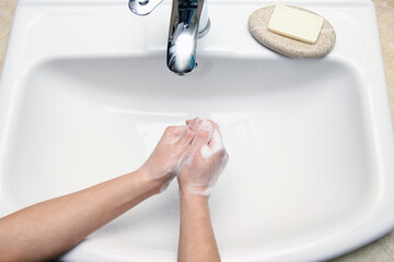 Wall Mural - A Hands with soap are washed under the tap with water. Clean from infection and dirt and virus. At home or in the hospital ablution office.