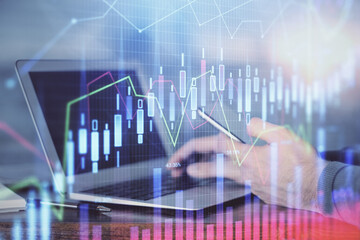 Double exposure of man's hands holding and using a digital device and forex graph drawing. Financial market concept.