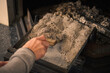 Main d'un homme qui nettoie le tiroir où sont tombées les cendres du bois de chauffage du feu de cheminée