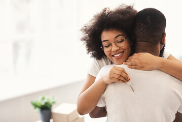 Happy African Couple Holding New House Key Embracing Standing Indoors