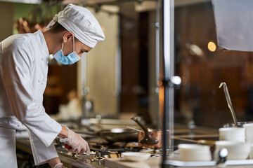 Gentleman in chef uniform switching on the gas stove