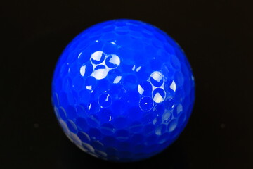 Close-up of a blue golf ball on a black background