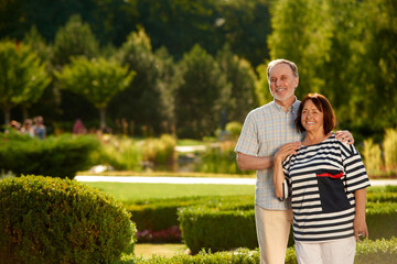 Smiling caucasian old couple outdoors. Married pair in a green summer park.