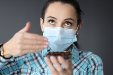 Woman in protective medical mask tries to smell coffee