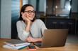 © Drobot Dean - Happy young woman in eyeglasses smiling while working with laptop