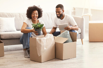 Happy African Couple Unpacking Moving Boxes Together In New Apartment