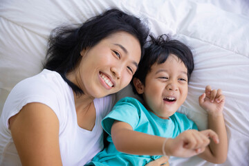 Authentic close up of happy mother and her son in a bed. Concept of new generation, family, parenthood, authenticity, connection.