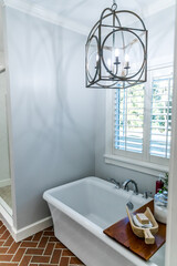 Large white renovated master bathroom bathtub with red brick floors