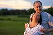 © DenisProduction.com - Loving husband hugs his wife from behind. Green field background.