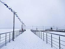 Resort Park In Winter. Snow Covered Pier, Path, Flags