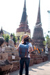 Asian woman tourists carrying a backpack and wearing a hat Visit Wat Yai Chaimongkol, the historical archaeological site of Phra Nakhon, Ayutthaya.