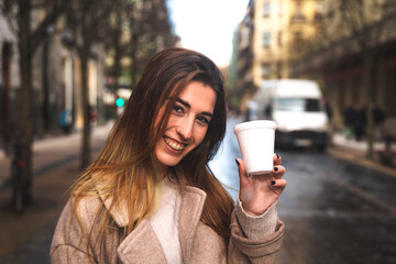 Young caucasian woman taking a take away coffe while walking through the downtown at Donostia-San Sebastian; Basque Country.