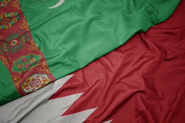 waving colorful flag of bahrain and national flag of turkmenistan.