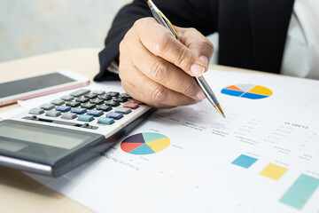 Asian accountant working and analyzing financial reports project accounting with chart graph and calculator in modern office, finance and business concept.