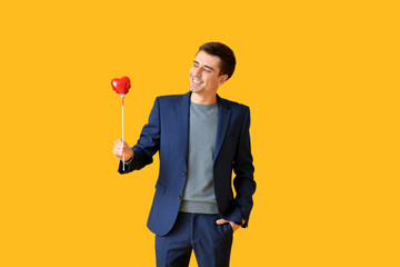 Poster - Handsome man with red heart on stick against color background