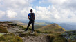 © Chris - A man in hiking outfit standing long a narrow hiking pathway, while hiking to Speikkogel, Austrian Alps. The mountains around are lush green. A bit of overcast. Achievement. Endless mountain chains