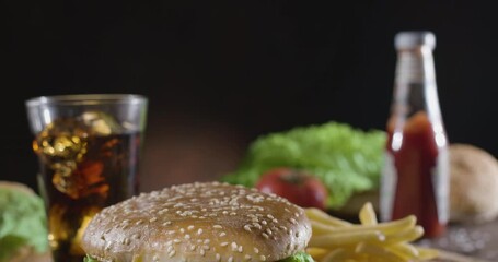 Wall Mural - Camera pans slowly across the fast food dining table - sweet carbonated drink and potato fries, stopping in front of a juicy hamburger. Blackmagic Pocket Cinema Camera 6K.