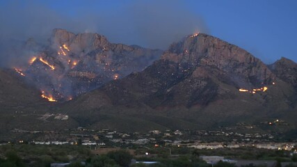 Wall Mural - Smoky glowing Wildfire outbreak engulfing Mountains overlooking city, static shot