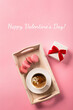 Sweet rose macaroons, present gift box and cup of coffee on pink background. Top view, copy space.