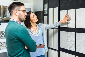 Wall Mural - Middle age man choosing ceramic tiles and utensils for his home bathroom and female seller helps him to make right decision