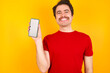 © Roquillo - Smiling Young Caucasian man wearing red t-shirt standing against yellow background Mock up copy space. Hold mobile phone with blank empty screen
