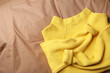 © New Africa - Beautiful yellow warm sweater on brown bedsheet, top view. Space for text
