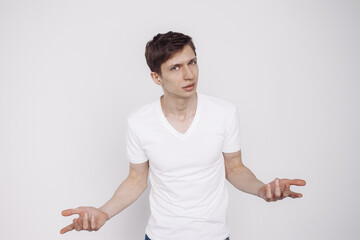 Portrait of young man in a white t-shirt who shows the question, isolated on white background.