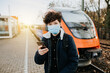 Nutzung von öffentlichen Verkehrsmitteln während einer Pandemie junger Mensch mit Maske am Bahnhof 