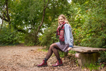 Attractive Woman Sitting On Bench In Autumnal Park