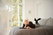 © Jakob Helbig/Westend61 - Happy senior woman with digital tablet lying on bed in bedroom