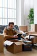 © Giorgio Fochesato/Westend61 - Young man unpacking books from box while moving in new loft apartment