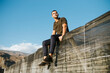 © Miguel Frias/Westend61 - Young male farmer sitting on top of greenhouse roof against blue sky during sunny day