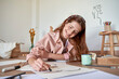 © Veam/Westend61 - Smiling female artist drawing art on paper while lying at home