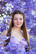 © Clare Seibel-Barnes/Austockphoto - Front on portrait of a happy smiling teen girl with long brown hair among purple jacaranda flowers
